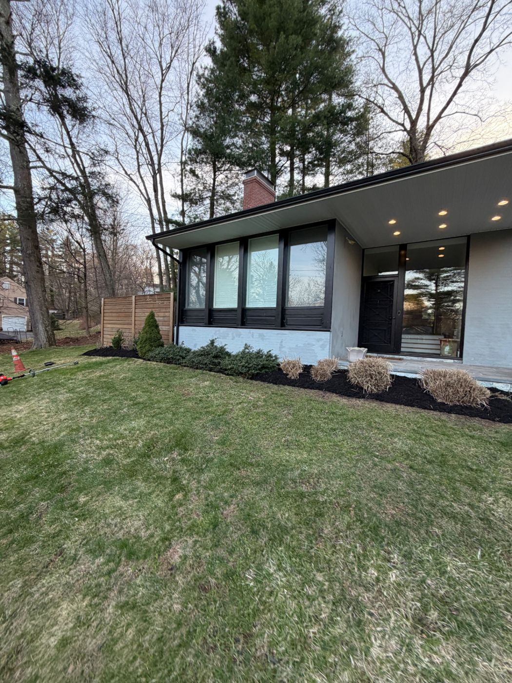 Black mulch and maintained garden beds beside a modern house