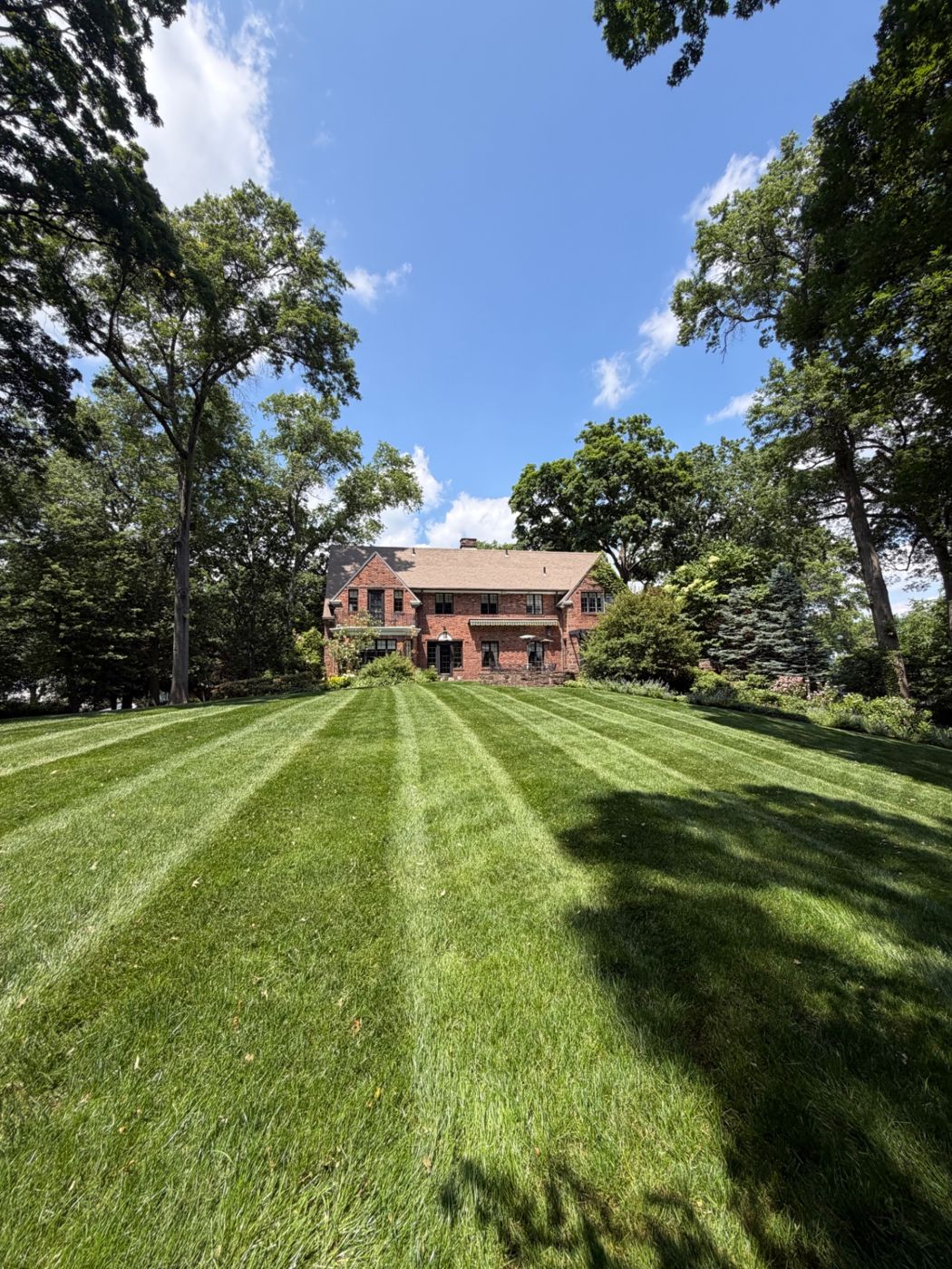 Professionally striped lawn in front of a brick house in West Hartford